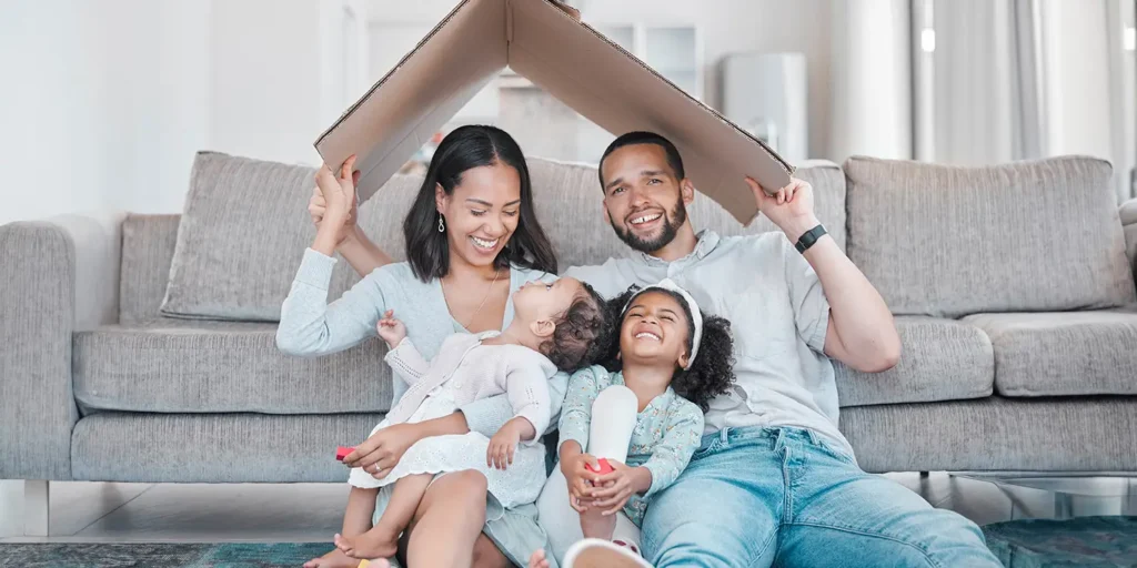 Nantes Guide To Moving Home. Photo of happy family ready to move home and holding card over their head pretending it's a roof.