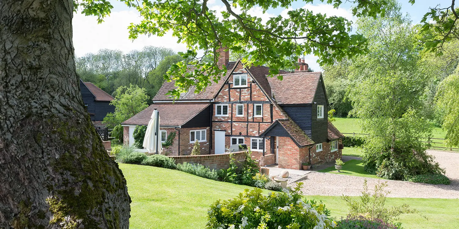 Land Registration: A guide to Compulsory & Voluntary land registration. Photo of old country cottage surrounded by lush fields and trees