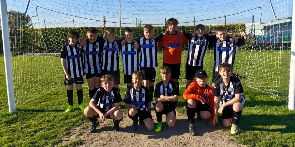 Dorchester Stars Under 11s football team in Nantes-sponsored kits standing proudly in goal, showcasing community support in Dorchester