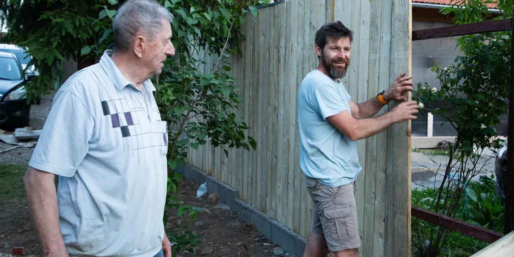 Two neighbours beside a garden fence, illustrating a potential boundary dispute between neighbouring properties in Dorset